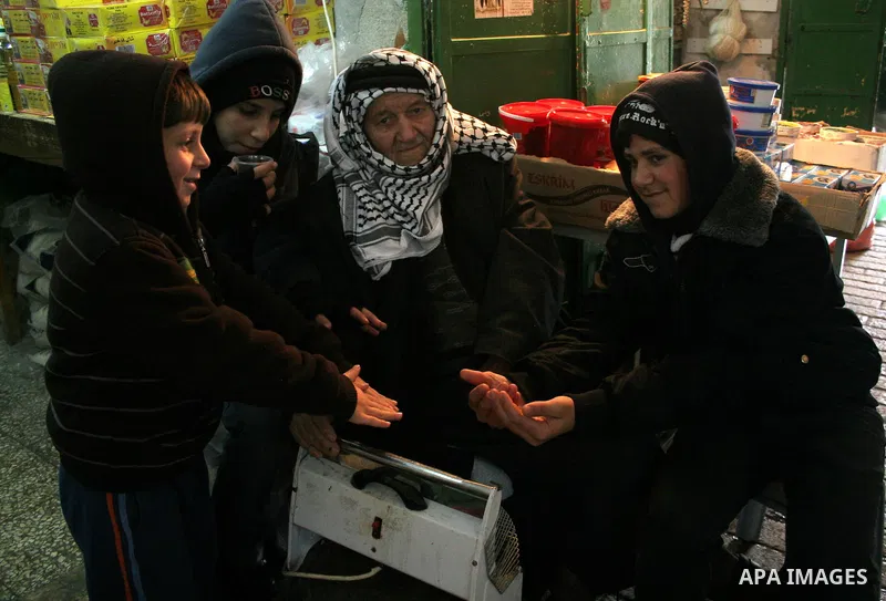 Palestinian men sit by a fire in the market in the old city of West Bank city of Hebron January 25, 2010. Photo by Najeh Hashlamoun