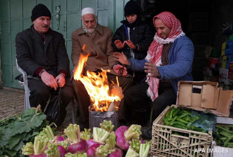 Palestinian men sit by a fire in the market in the old city of West Bank city of Hebron January 25, 2010. Photo by Najeh Hashlamoun