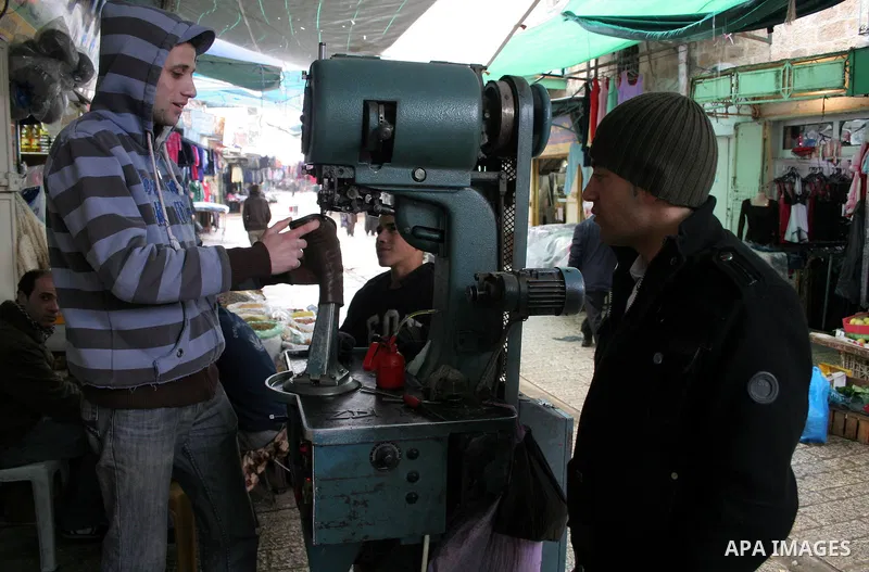 A Palestinian shoemaker talks behind a sewing machine at his workshop in the market in the old city of West Bank city of Hebron January 25, 2010. Photo by Najeh Hashlamoun