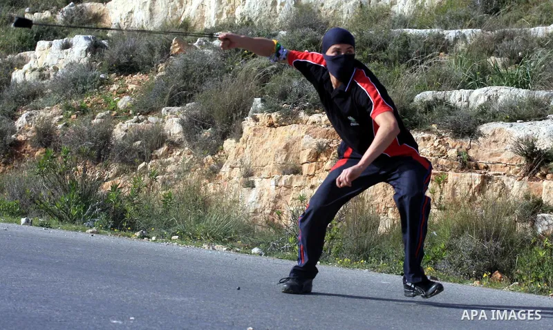 Palestinian protester uses a sling to throw a stone towards Israeli troops during a protest by Palestinians over water supplies in the West Bank village of Nabi Salah, Friday, Feb. 19, 2010. The water supply is used by J...