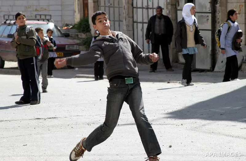 A Palestinian youth throws stones at an Israeli army vehicle in the West Bank city of Hebron on February 23, 2010. , after Israel's Prime Minister Benjamin Netanyahu was quoted in a statement as saying that the Tomb of t...