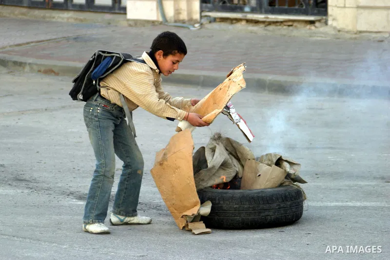 A Palestinian boy burning tyre towards Israeli army troops in the West Bank city of Hebron February 23 2010, after Israel's Prime Minister Benjamin Netanyahu was quoted in a statement as saying that the Tomb of the Patri...