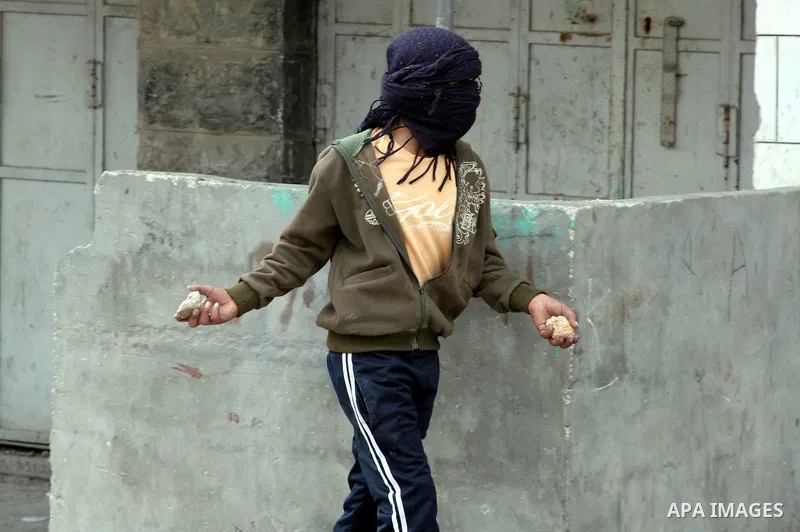 Palestinian youth throws stones at Israeli soldiers in the West Bank city of Hebron February 24, 2010, after Israel's Prime Minister Benjamin Netanyahu was quoted in a statement as saying that the Tomb of the Patriarchs,...