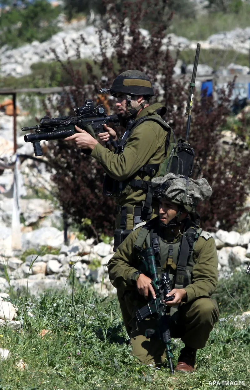 An Israeli soldier aims his gun at Palestinian youths during clashes with Palestinian protesters in the West Bank village of Iraq Borin near the West Bank city of Nablus, 20 March 2010. According to local media reports,...