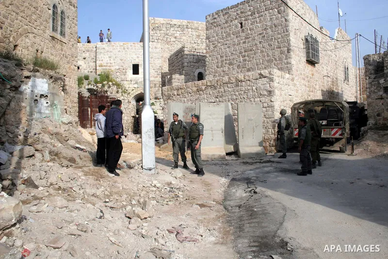 Israeli soldiers stand guard as a bulldozer moves a road block in the old city West Bank of Hebron on 24 March 2010. Talks between US President Barack Obama and Israeli Prime Minister Benjamin Netanyahu failed to produce...
