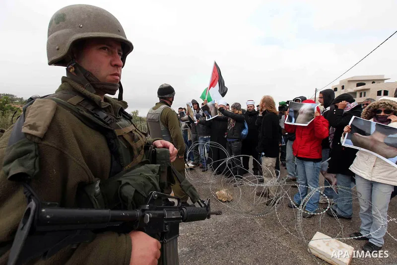 Israeli soldiers stand guard as Palestinian Chief Islamic Justice of Tayssir al-Tamimi and Palestinian Muslim stand next to demonstrators during a protest against Israel's separation barrier in the West Bank village of M...