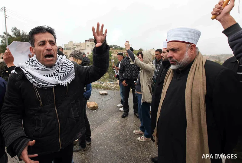 Israeli soldiers stand guard as Palestinian Chief Islamic Justice of Tayssir al-Tamimi and Palestinian Muslim stand next to demonstrators during a protest against Israel's separation barrier in the West Bank village of M...