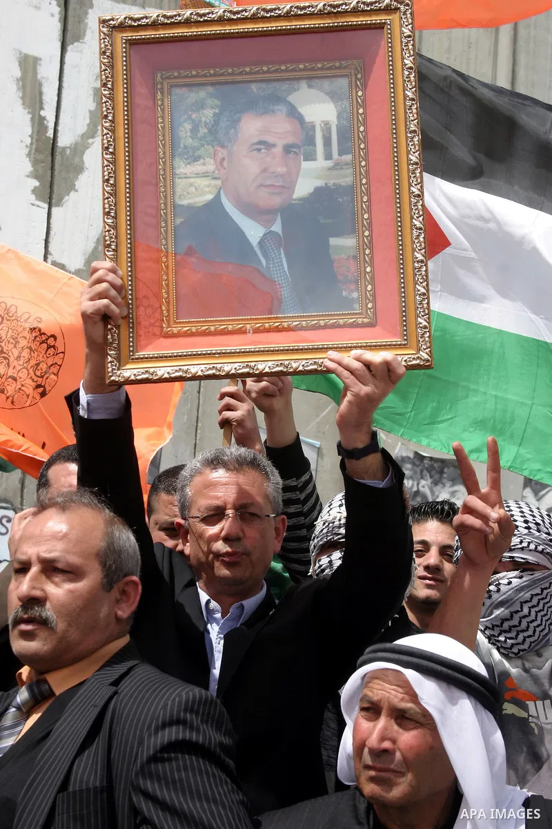 A Palestinian Parliament member, Mustafa Al-Barghouti holds a picture of Fatah leader, Abbas Zaki during a demonstration next a section of Israel's separation barrier in the West Bank town of Bethlehem, Monday, March, 29...