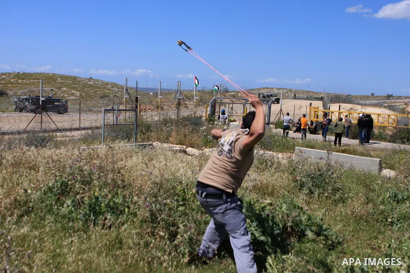 A Palestinian protester uses a sling to hurl stones towards Israeli border police during a demonstration marking Land Day in the West Bank village of Budros near Ramallah, Tuesday, March 30, 2010. Land Day commemorates t...