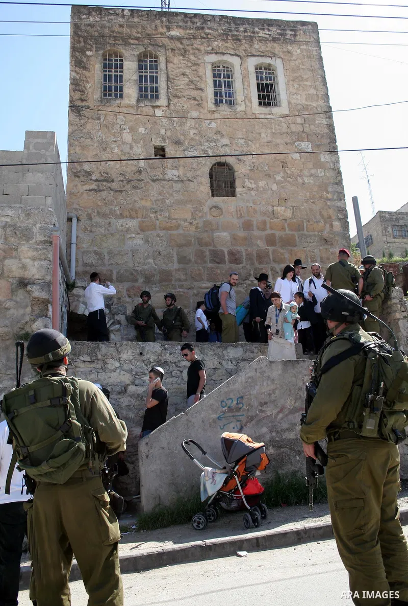Israeli soldiers escort Jewish settlers as they head to visit the tomb of Atnaeil Ben Kinaz in the occupied West Bank city of Hebron on March 31, 2010. The United States wants a four-month Israeli building freeze in occu...