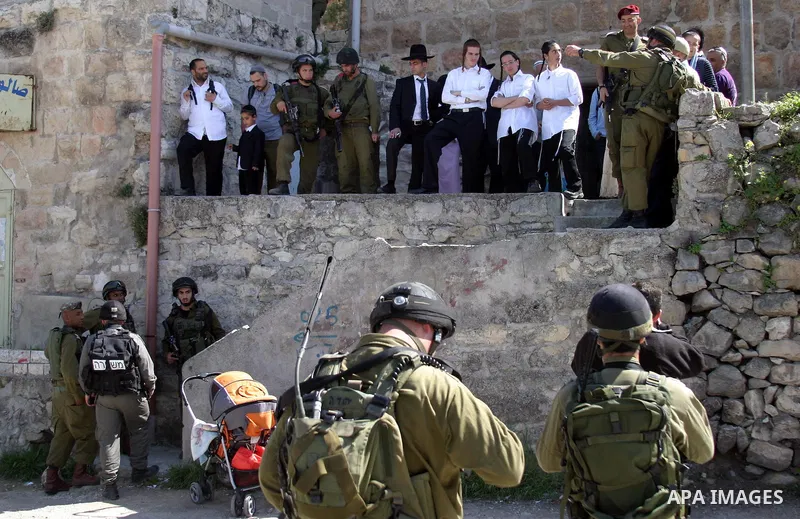 Israeli soldiers escort Jewish settlers as they head to visit the tomb of Atnaeil Ben Kinaz in the occupied West Bank city of Hebron on March 31, 2010. The United States wants a four-month Israeli building freeze in occu...
