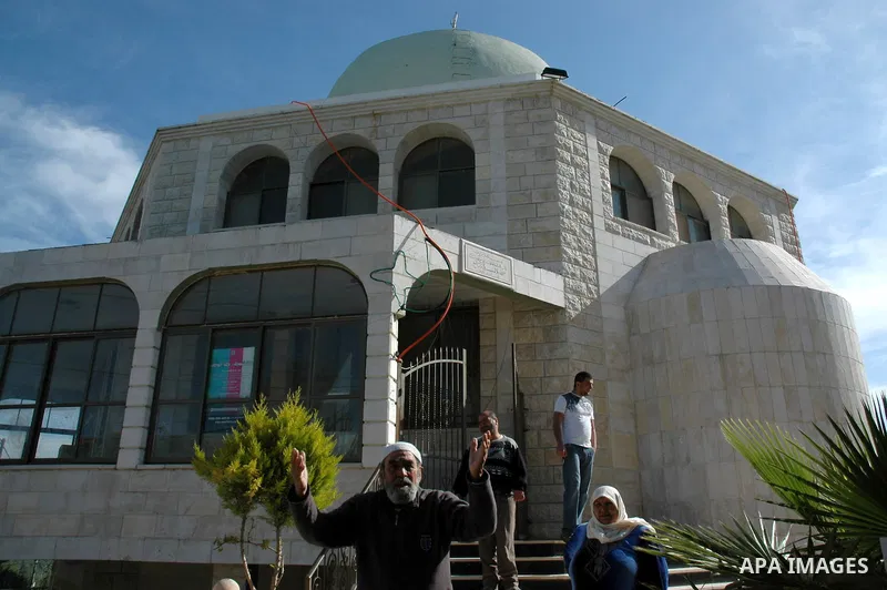 Palestinians stand outside the Bilal Ibn Rabah mosque in the West Bank village of Hawara, near the West Bank city of Nablus, on April 14, 2010. Israeli settlers desecrated a mosque and set fire to two cars in the occupie...