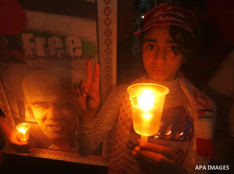 A Palestinian girl stands next to a poster of Ahmed Saadat, jailed leader of the Popular Front for the Liberation of Palestine (PFLP), as she takes part in a candlelight vigil to mark Palestinian Prisoners' Day in Rafah...