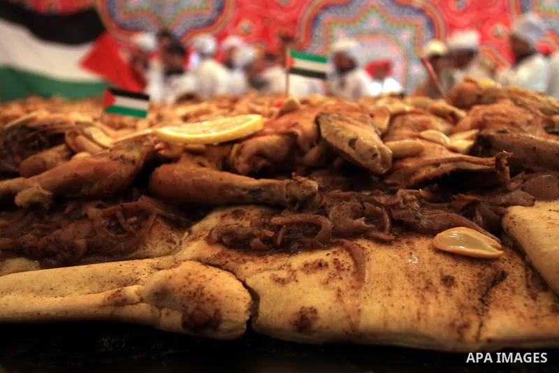 Palestinian chefs and media surround a huge portion of Musakhan, a traditional Palestinian dish made of chicken, flat bread, nuts and spices, on April 19, 2010 in the West Bank village of Arura, near Ramallah as they att...
