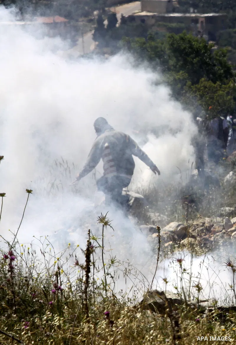 A Palestinian youth runs from tear gas fired by Israeli troops during a protest against the expansion of Israeli settlements in the West Bank village of Iraq Burin near city of Nablus on April 24,2010. Photo by Nedal Sht...