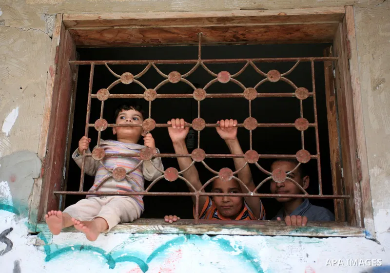 Palestinian children look at Palestinians paricipate in a rally marking the anniversary of the "Nakba", Arabic for catastrophe, in the Jabaliya refugee camp, northern Gaza Strip, Friday, May 14, 2010. The 62nd anniversar...