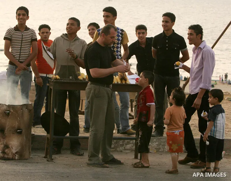 Palestinians eat corn at the beach of Gaza City May 14, 2010. Photo by Ali Jaad Allah.