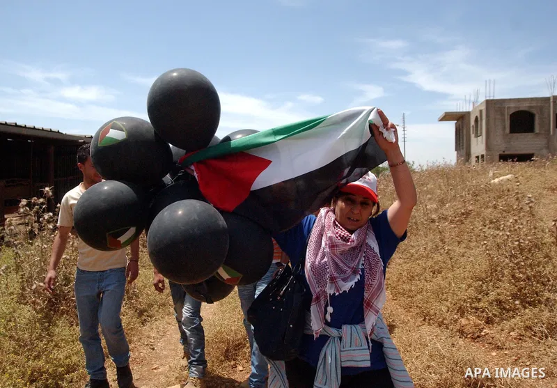 Palestinian woman holds black balloons during a demonstration against the expansion of Jewish settlements in the West Bank village of Iraq Burin, south of Nablus, on May 15, 2010 as Palestinians marked 62 years since the...