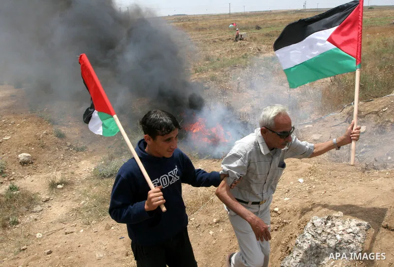 Palestinians wave their national flags during a protest on May 19, 2010, on the outskirts of Gaza City against the military zone Israel created on Palestinian land as a buffer between its border areas and the Hamas-run G...