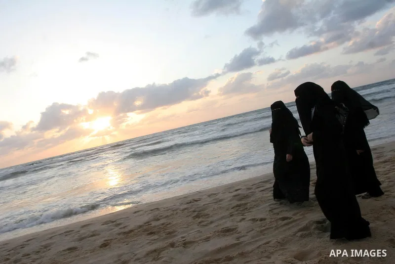 Palestinian women walk during sunset on the beach of Gaza City May 19, 2010. Photo by Ashraf Amra
