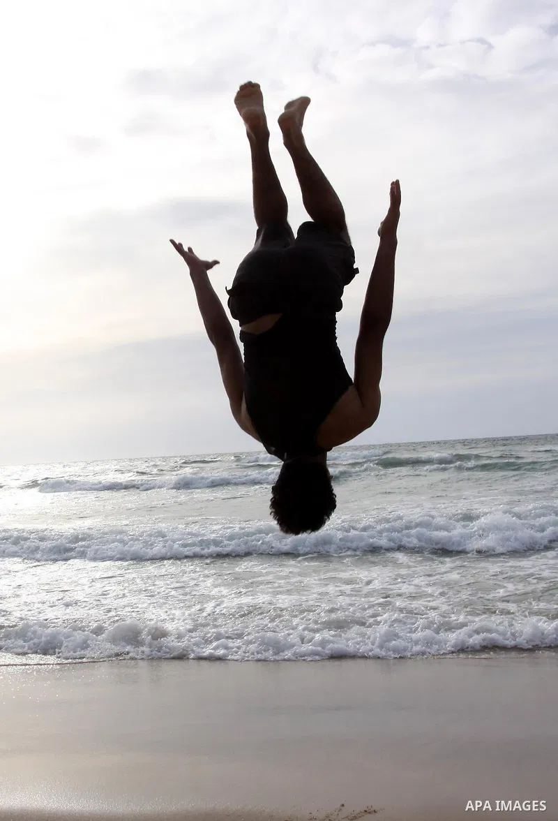 A Palestinian youth jumps on the beach of Gaza City on May 21,2010. Photo by Mohammed Asad