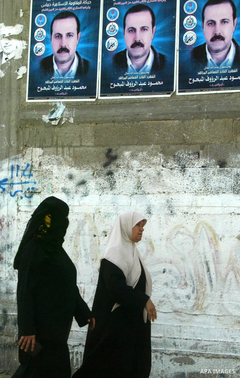 Palestinians walk past a poster image of assassinated senior Hamas militant Mahmoud al-Mabhouh in Jabalya, northern Gaza Strip on May 24, 2010, Australia has ordered the expulsion of an Israeli diplomat working in the Is...