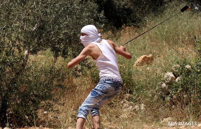 A Palestinian youth uses a sling to hurl stones at Israeli soldiers during clashes in the West Bank village of Nabi Saleh, on 28 May 2010. Palestinians protest weekly against the neighbouring Jewish settlement of Halamis...