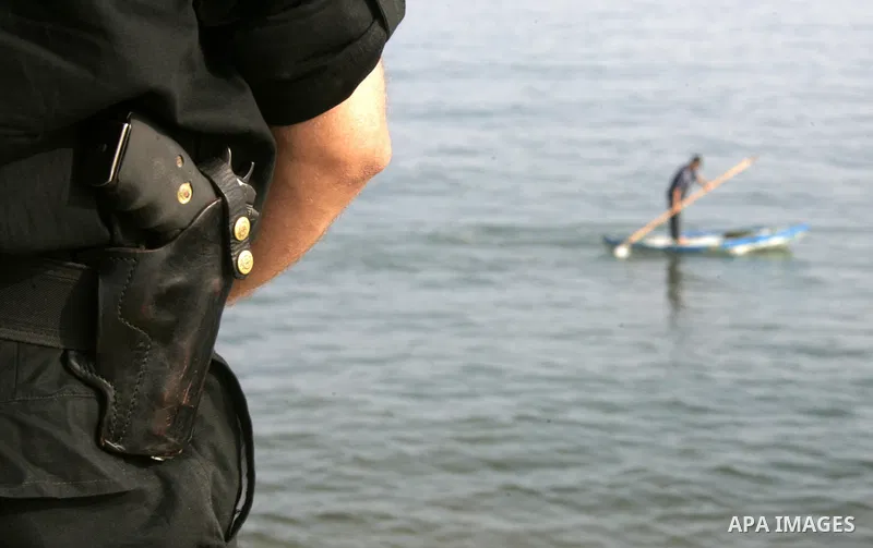 Palestinian Hamas policeman looks at Palestinian fisherman in the port of Gaza City on May 31, 2010. At least 10 people were killed in an Israeli Navy raid on a fleet of aid ships, most of them Turkish nationals, accordi...
