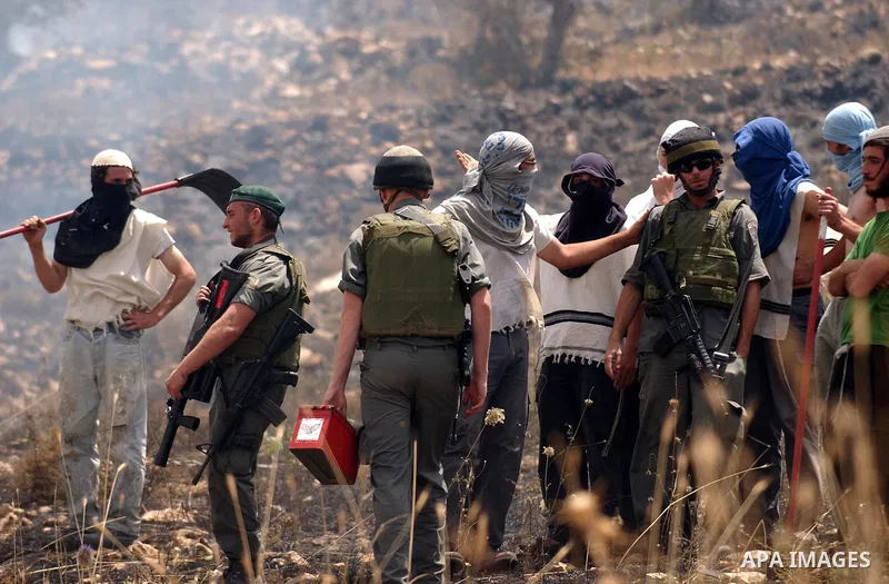 Masked Israeli settlers watch after Palestinian fields were set on fire in the village of Asira al-Qiblyia in the northern West Bank on June 2, 2010. According to Palestinian villagers, Jewish settlers from the nearby Yi...