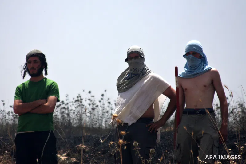 Masked Israeli settlers watch after Palestinian fields were set on fire in the village of Asira al-Qiblyia in the northern West Bank on June 2, 2010. According to Palestinian villagers, Jewish settlers from the nearby Yi...