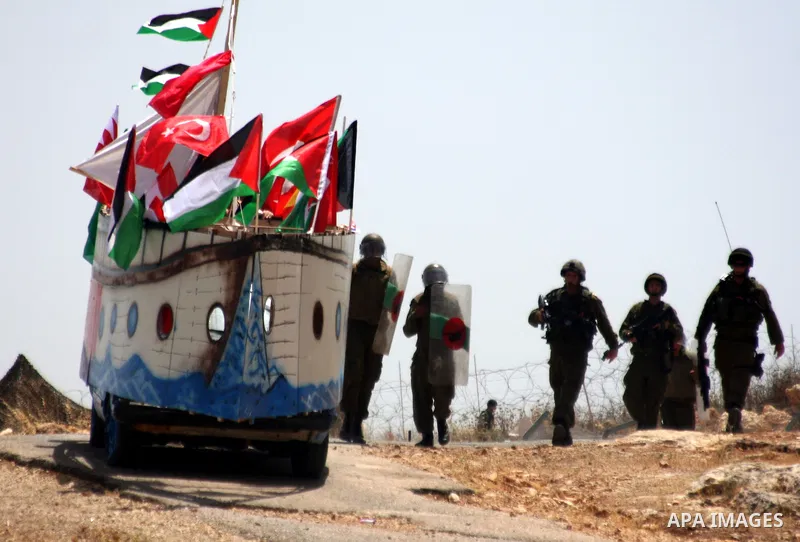 Israeli forces approach on June 4, 2010 a model of a ship depicting the Gaza-bound aid flotilla that was raided by Israeli naval forces on May 31, 2010, during a demonstration by Palestinian and foreign peace activists i...