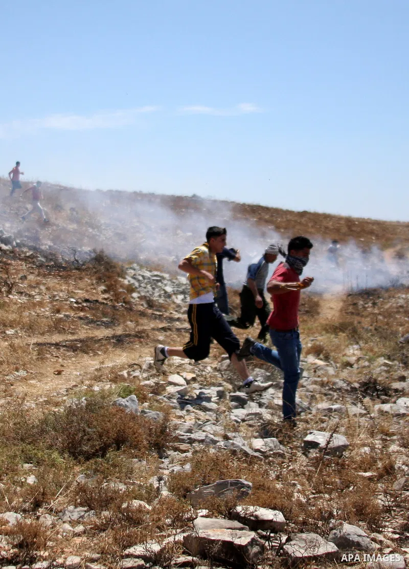 Palestinian youths run to protect themselves from the effects of tear gas, fired by Israeli forces during an anti-Israeli demonstration in the West Bank village of Iraq Burin, near the city of Nablus, Saturday, June 5, 2...