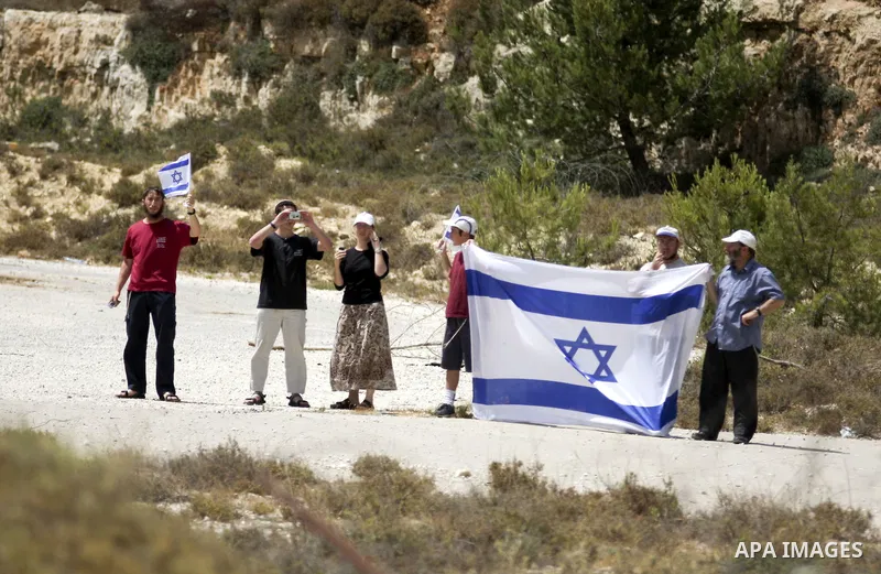 Israeli settlers hold up Israeli flag as Palestinians from the village of Bet In, north of Ramallah protest against Israeli occupation on June 11, 2010 near the Jewish settlement of Beit El. Photo by Eyad Jadallah