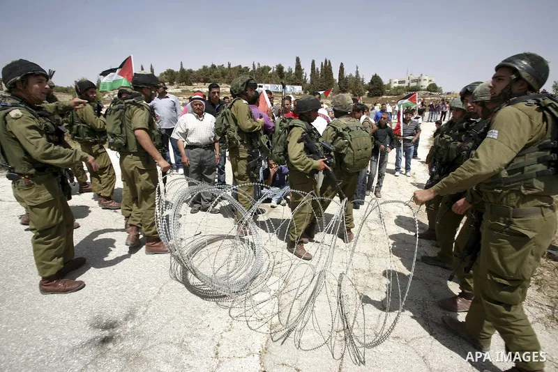 Israeli soldiers surround Palestinians from the village of Bet In, north of Ramallah, as they hold up their national flag during protest against Israeli occupation on June 11, 2010 near the Jewish settlement of Beit El....