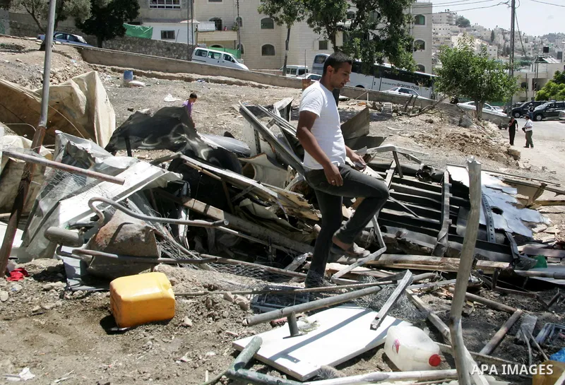 A Palestinian youth stands on the rubble of a house after an Israeli bulldozer destroys a Palestinian family house in east Jerusalem neighborhood of Silwan on June 15,2010, where Palestinian houses are threatened to be d...