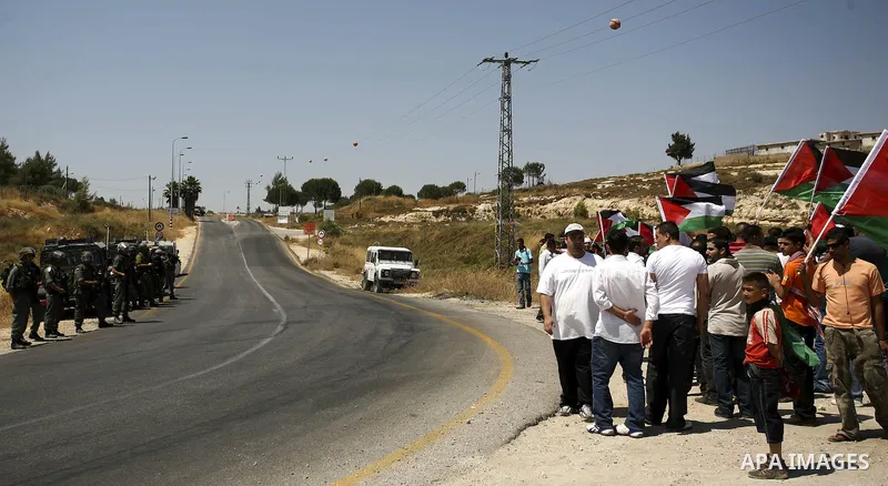 Palestinian protesters from the village of Bet In, north of Ramallah hold up their national flag during protest against Israeli occupation on June 18, 2010 near the Jewish settlement of Beit El. Photo by Eyad Jadallah