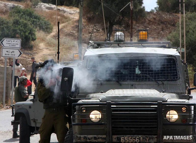 An Israeli soldier fires tear gas canisters at Palestinian demonstrators during a protest against the expansion of the nearby Jewish settlement of Halamish in the West Bank village of Nabi Saleh, Friday june ,25 2010. Ph...