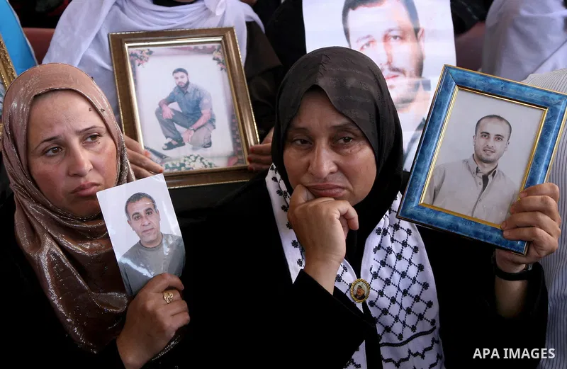 Palestinian women and children hold pictures of jailed relatives during a protest calling for the release of Palestinian prisoners from Israeli jails at the Red Cross office in Gaza City on June 28,2010. Photo by Ali Jad...