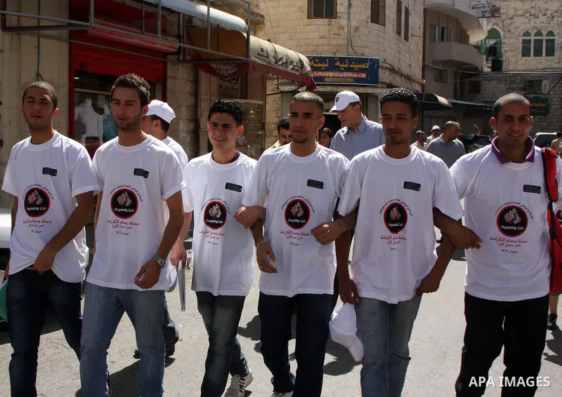 Palestinian volunteers attend a rally as they distribute a guidebook to boycott the settlements products in the West Bank city of Nablus, Monday June 28, 2010. The Palestinian authority launched a campaign of boycotting...