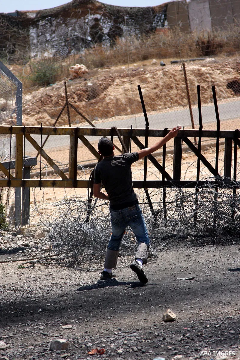 A Palestinian protester hurls stones at Israeli troops during a demonstration against Israel's separation barrier in the West Bank village of Bilin near Ramallah, Friday, July 2, 2010. Israel says the barrier is necessar...