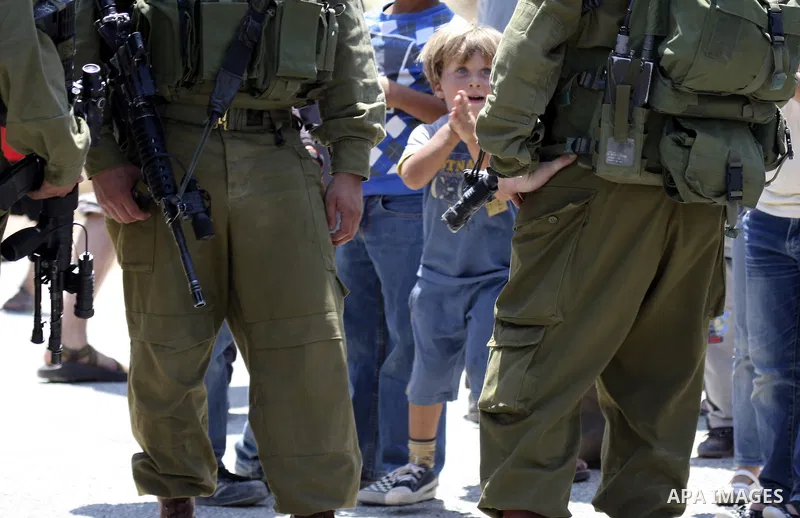 Israeli troops guard as Palestinian women and children shout slogans during a protest by locals, as well as foreign and leftwing Israeli peace activists, in Nabi Saleh, near Ramallah, on July 2, 2010 against the expropri...