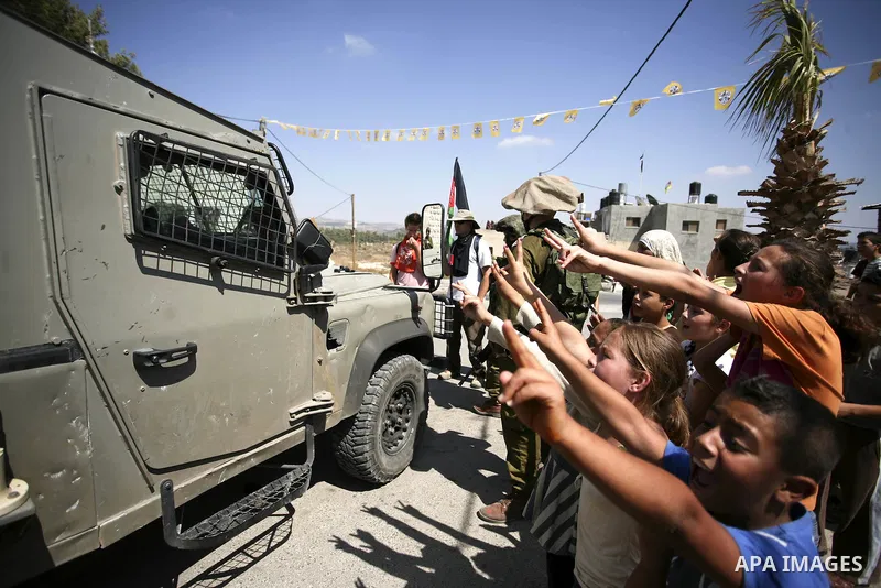 Israeli troops guard as Palestinian women and children shout slogans during a protest by locals, as well as foreign and leftwing Israeli peace activists, in Nabi Saleh, near Ramallah, on July 2, 2010 against the expropri...