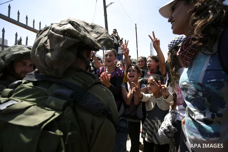 Israeli troops guard as Palestinian women and children shout slogans during a protest by locals, as well as foreign and leftwing Israeli peace activists, in Nabi Saleh, near Ramallah, on July 2, 2010 against the expropri...