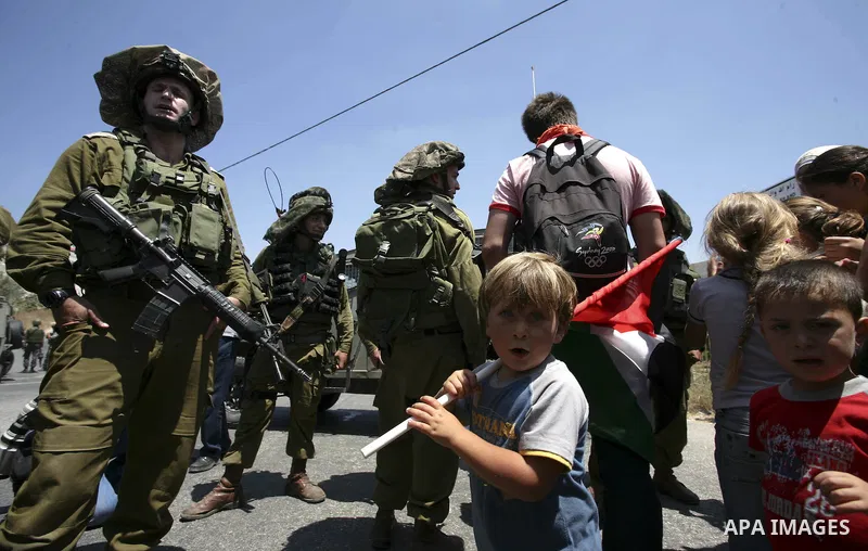 Israeli troops guard as Palestinian women and children shout slogans during a protest by locals, as well as foreign and leftwing Israeli peace activists, in Nabi Saleh, near Ramallah, on July 2, 2010 against the expropri...
