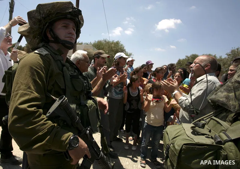 Israeli troops guard as Palestinian women and children shout slogans during a protest by locals, as well as foreign and leftwing Israeli peace activists, in Nabi Saleh, near Ramallah, on July 2, 2010 against the expropri...