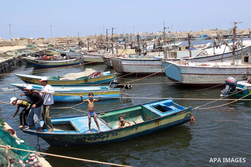 Palestinian boys enjoy swimming at the port of Gaza city on July 5,2010. A Palestinian fisherman was wounded by a shell fired by Israel's navy, Palestinian medics said. Photo by Mohammed Asad