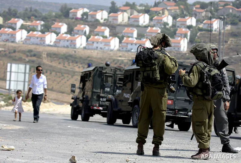 A Palestinian man walks past Israeli soldiers during a protest against the expansion of the Israeli settlements at Nabi Salah village near the West Bank City of Ramallah, on 09 July 2010. Photo by Eyad Jadallah