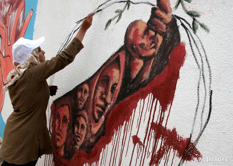 A Palestinian woman paints part of a wall painting made to support attempts to break the Israeli naval blockade on Gaza, at the sea port in Gaza City, Thursday, July 15, 2010. A Libyan ship carrying aid for the impoveris...