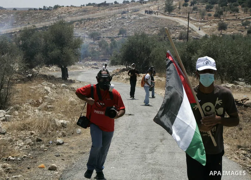 Palestinian protesters run for cover from tear gas fired by Israeli soldiers during a protest by Palestinian, Israeli and foreign activists against Israel's separation barrier outside the West Bank village of Bilin, near...