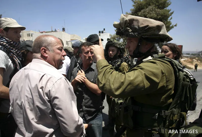 Palestinian youths taunt an Israeli officer during a demonstration against the expansion of the nearby Jewish settlement of Halamish in the West Bank village of Nabi Saleh near Ramallah, Friday, July 16, 2010. Photo by E...